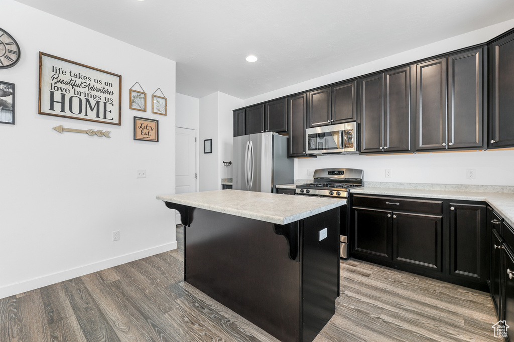 Kitchen with a kitchen bar, a center island, hardwood / wood-style floors, and stainless steel appliances