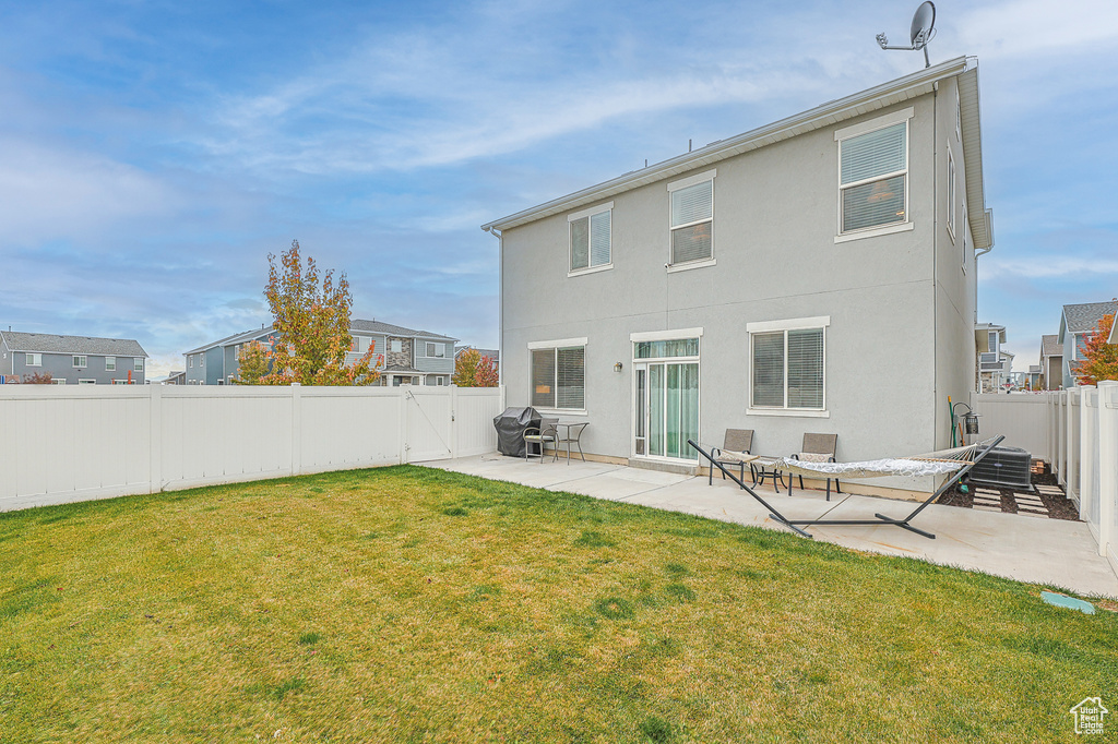 Back of house featuring a lawn and a patio