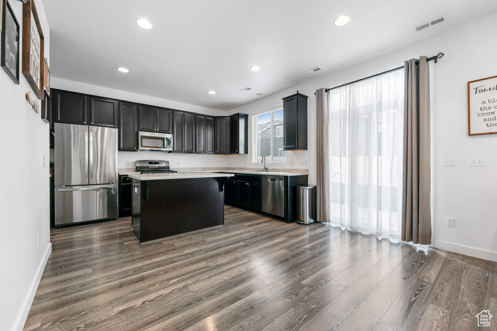 Kitchen with sink, a kitchen island, dark wood-type flooring, and appliances with stainless steel finishes