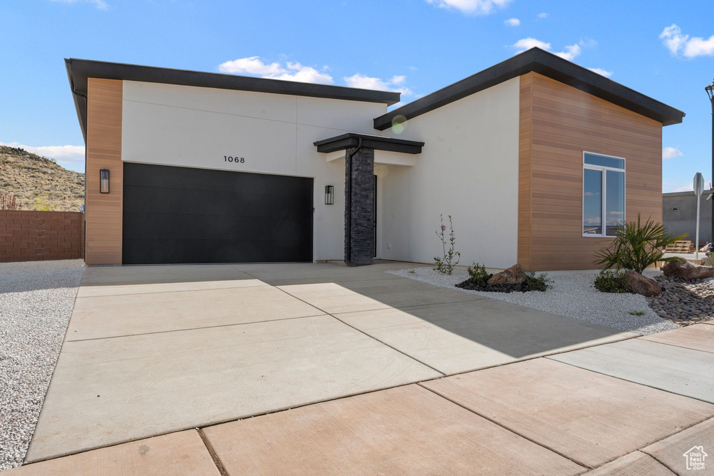 Modern home featuring fence, stucco siding, a garage, and concrete driveway