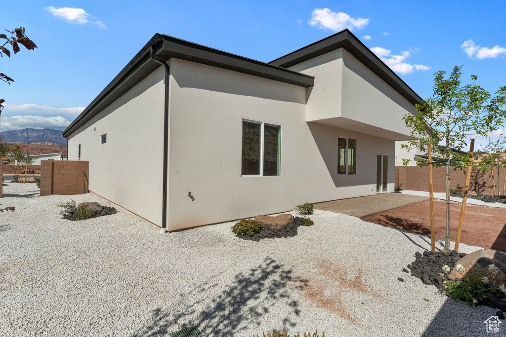 Rear view of property featuring a patio area, stucco siding, fence, and a mountain view