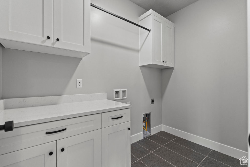 Laundry room featuring electric dryer hookup, baseboards, washer hookup, cabinet space, and dark tile patterned flooring