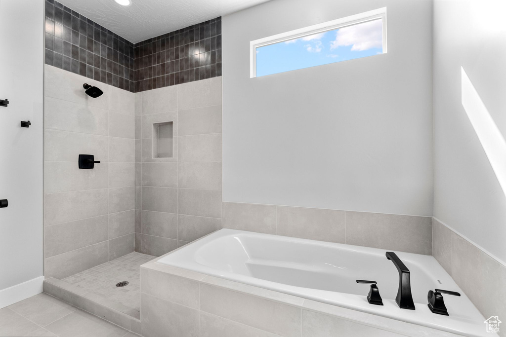 Bathroom featuring tile patterned floors, a garden tub, and tiled shower