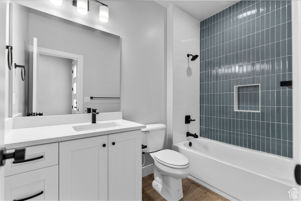 Bathroom with toilet, vanity, wood finished floors, and tub / shower combination