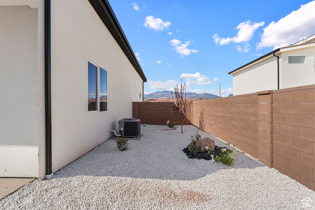 View of property exterior with cooling unit, a mountain view, stucco siding, and a fenced backyard