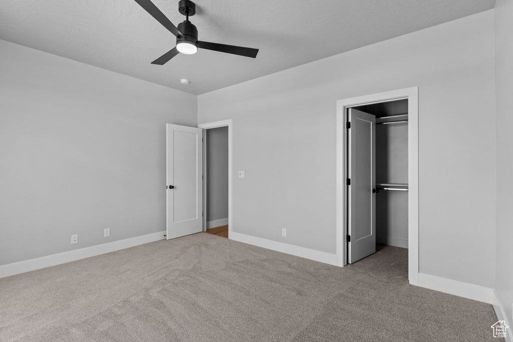 Unfurnished bedroom with a spacious closet, baseboards, carpet flooring, and a closet