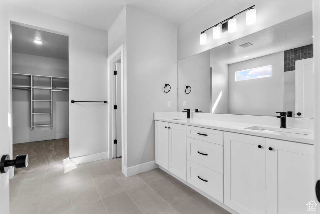 Full bath featuring tile patterned floors, double vanity, a sink, and a walk in closet
