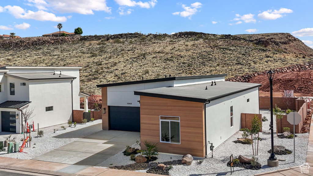 Rear view of house featuring a mountain view, fence, stucco siding, and concrete driveway