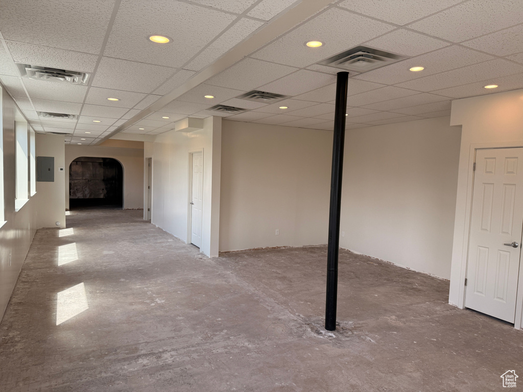 Finished below grade area featuring arched walkways, electric panel, recessed lighting, and visible vents