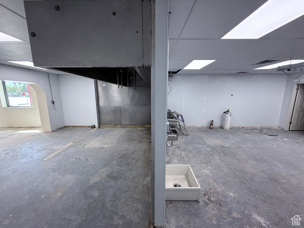 Basement featuring arched walkways and a paneled ceiling