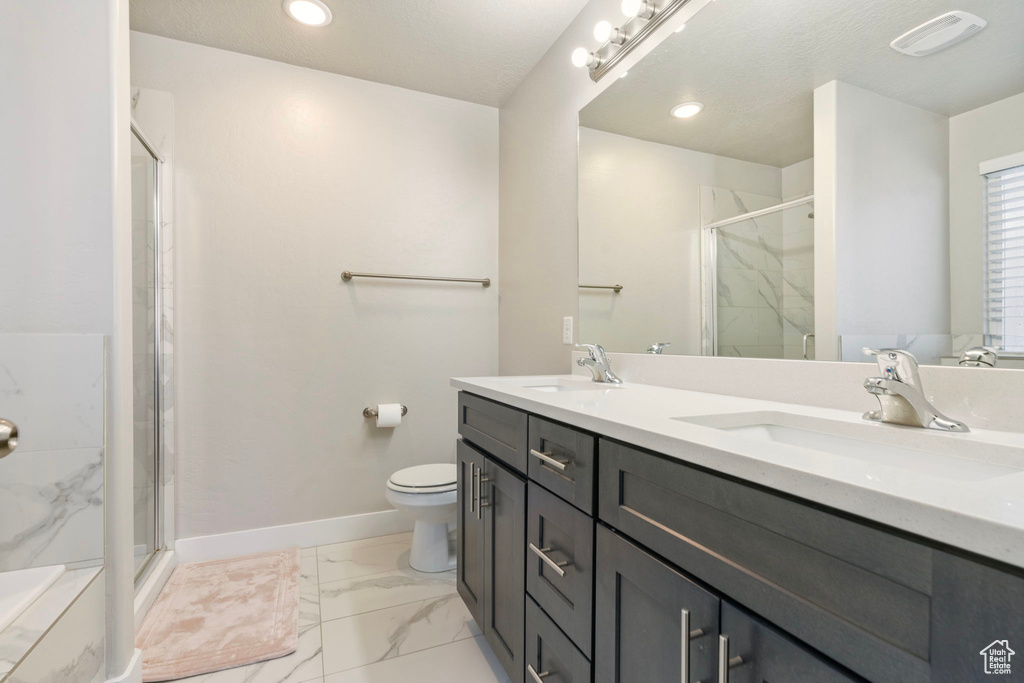 Bathroom featuring vanity, a shower with shower door, and toilet