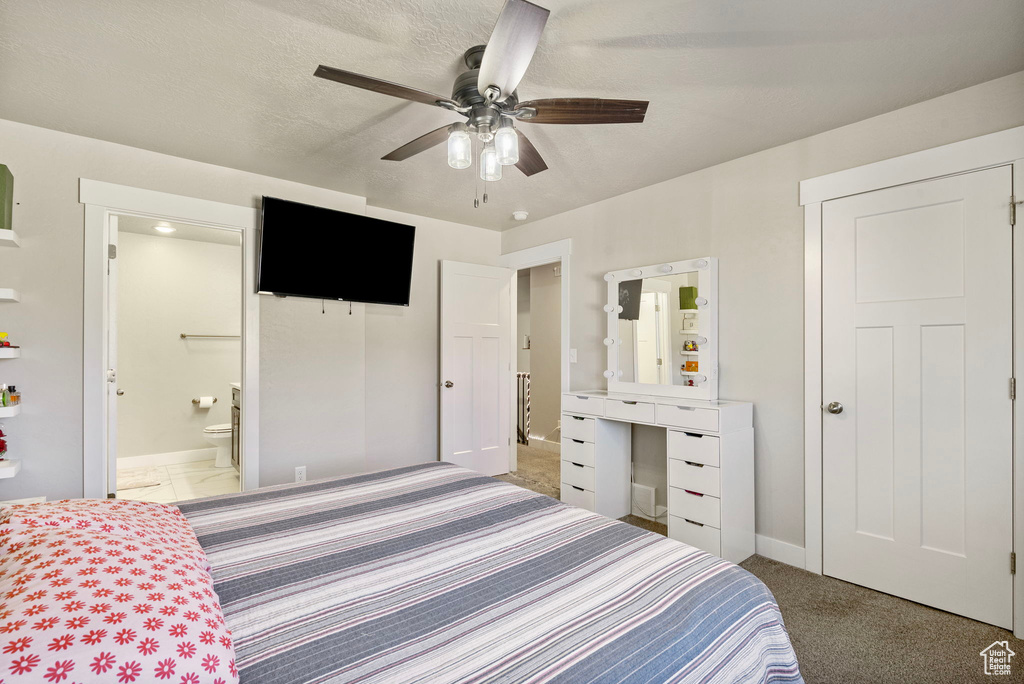 Carpeted bedroom with a textured ceiling, ensuite bath, and ceiling fan