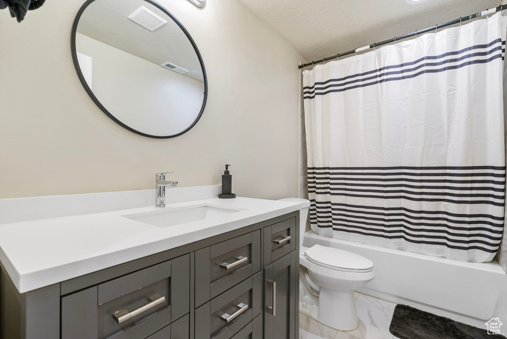 Full bathroom with shower / tub combo with curtain, vanity, a textured ceiling, and toilet