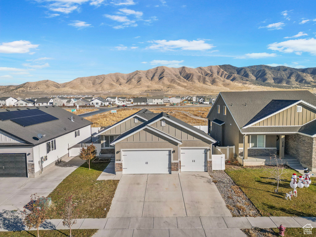 View of front of house with a mountain view, a front lawn, and a garage