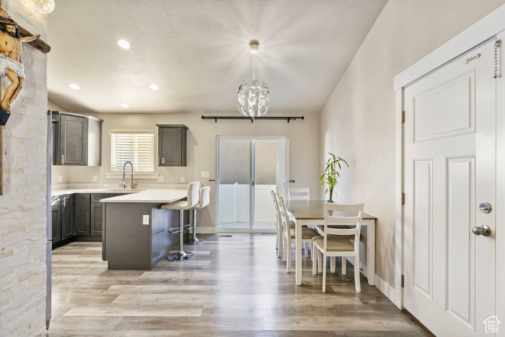 Dining space featuring sink, an inviting chandelier, a textured ceiling, and light wood-type flooring