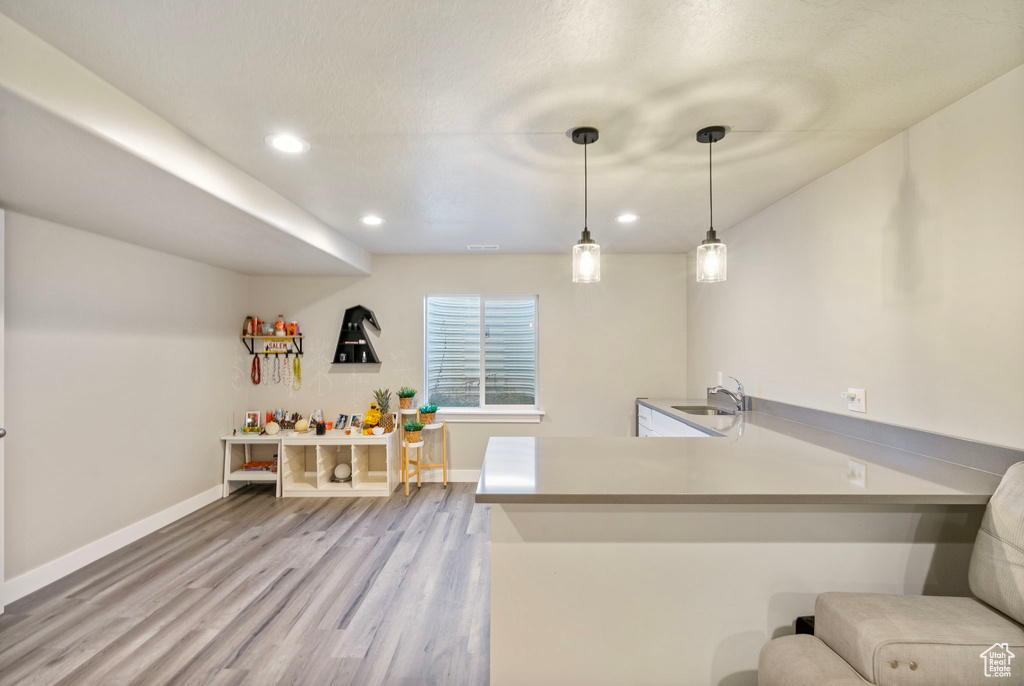 Bar with sink, hanging light fixtures, and light hardwood / wood-style flooring