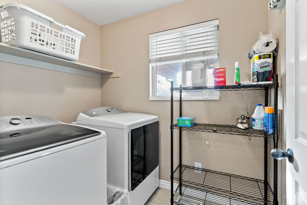 Laundry area featuring independent washer and dryer and light tile patterned floors