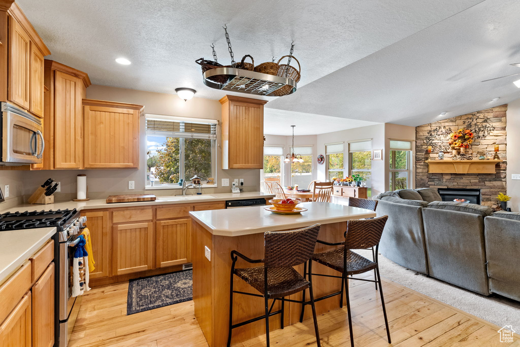 Kitchen with a center island, stainless steel appliances, light hardwood / wood-style flooring, and a healthy amount of sunlight