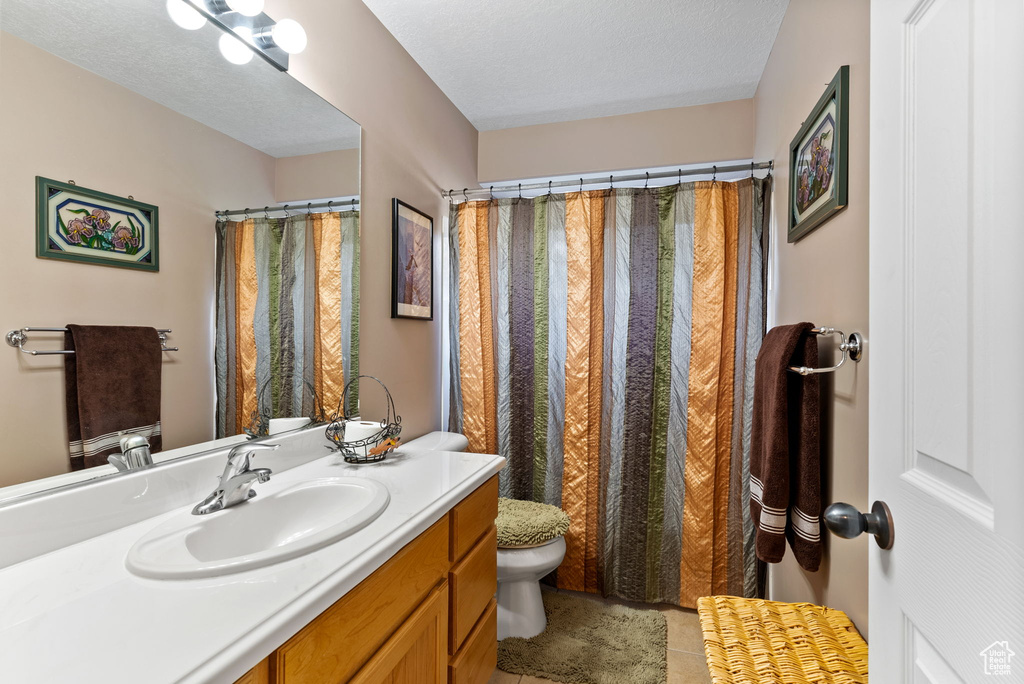 Bathroom featuring vanity, tile patterned flooring, a shower with shower curtain, toilet, and a textured ceiling