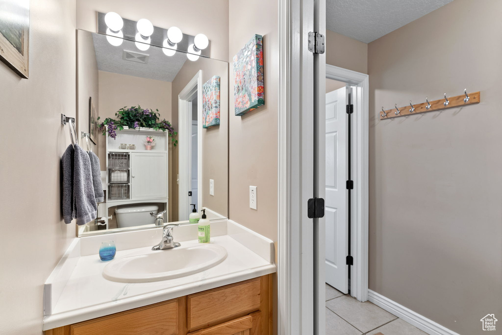 Bathroom featuring toilet, a textured ceiling, vanity, and tile patterned floors