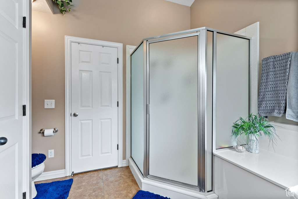 Bathroom featuring toilet, tile patterned floors, and an enclosed shower