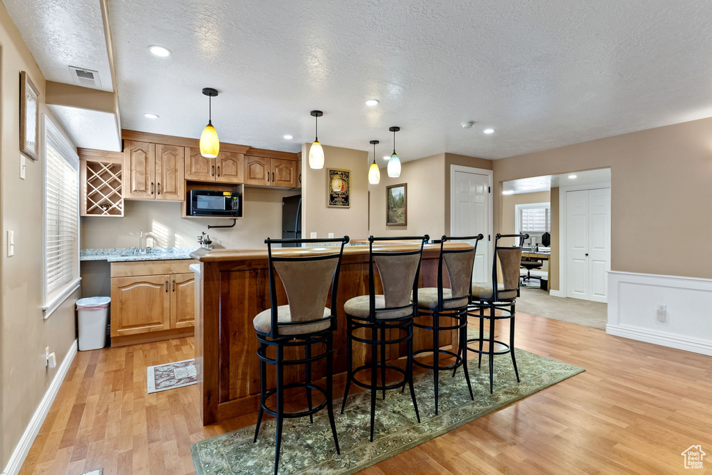 Kitchen featuring sink, decorative light fixtures, a textured ceiling, and light wood-type flooring