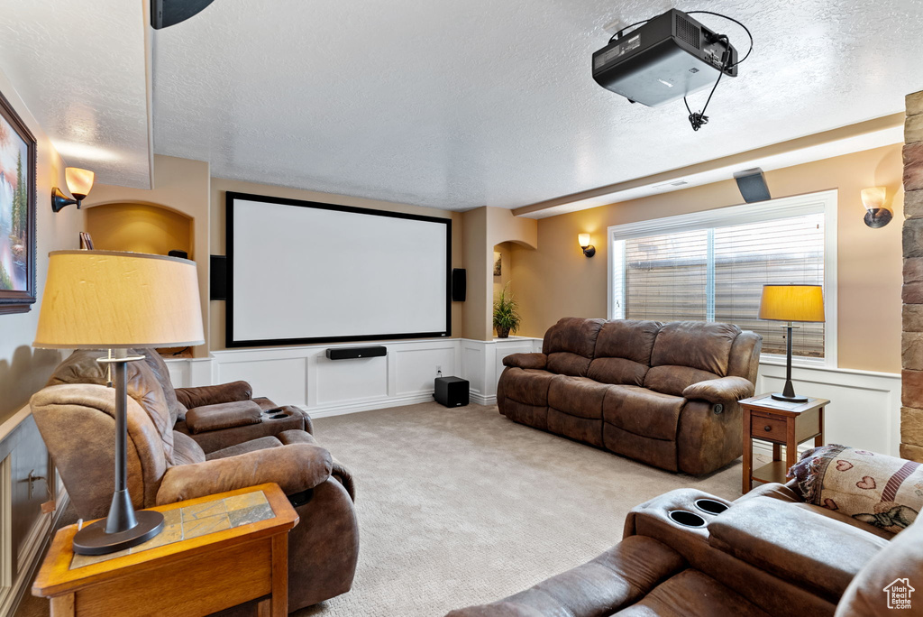 Carpeted home theater featuring a textured ceiling