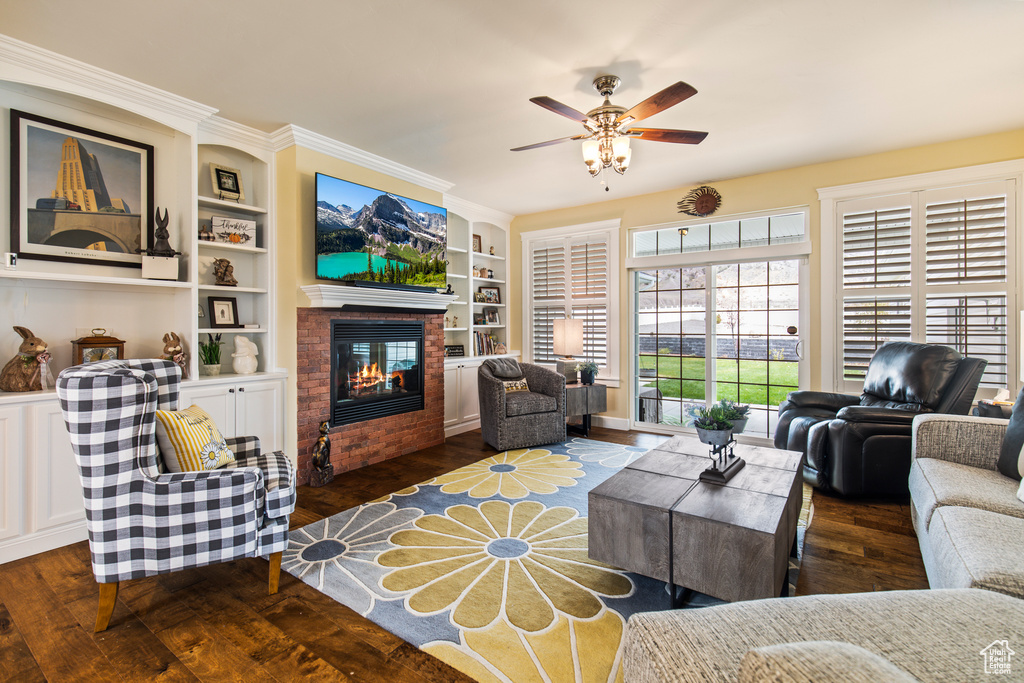 Living room featuring dark hardwood / wood-style floors, built in features, ceiling fan, and ornamental molding