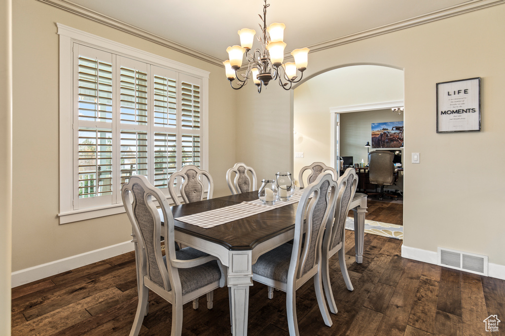 Dining space with ornamental molding, dark wood-type flooring, and a notable chandelier