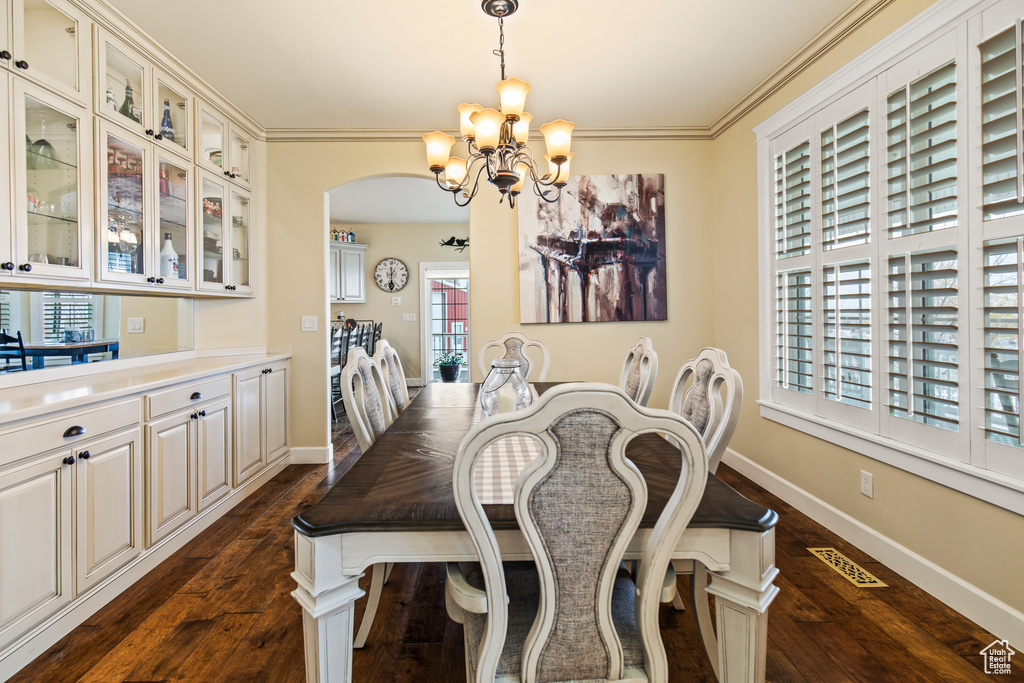 Dining space with a chandelier, dark hardwood / wood-style floors, and crown molding