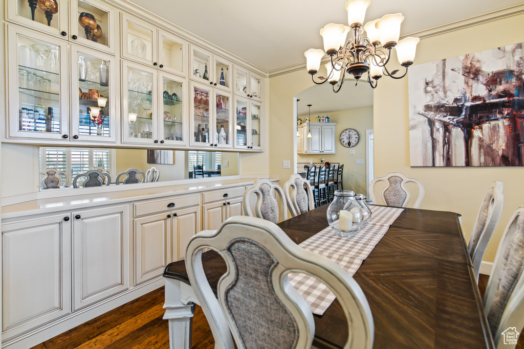 Dining room with dark hardwood / wood-style floors and a notable chandelier