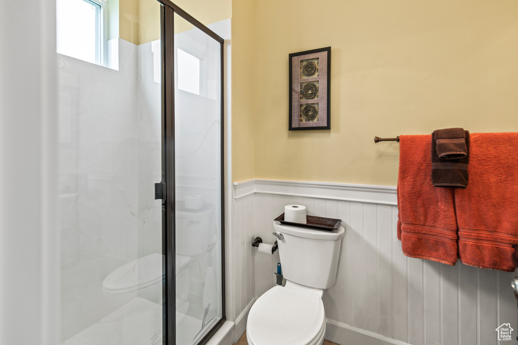 Bathroom featuring a shower with door and toilet