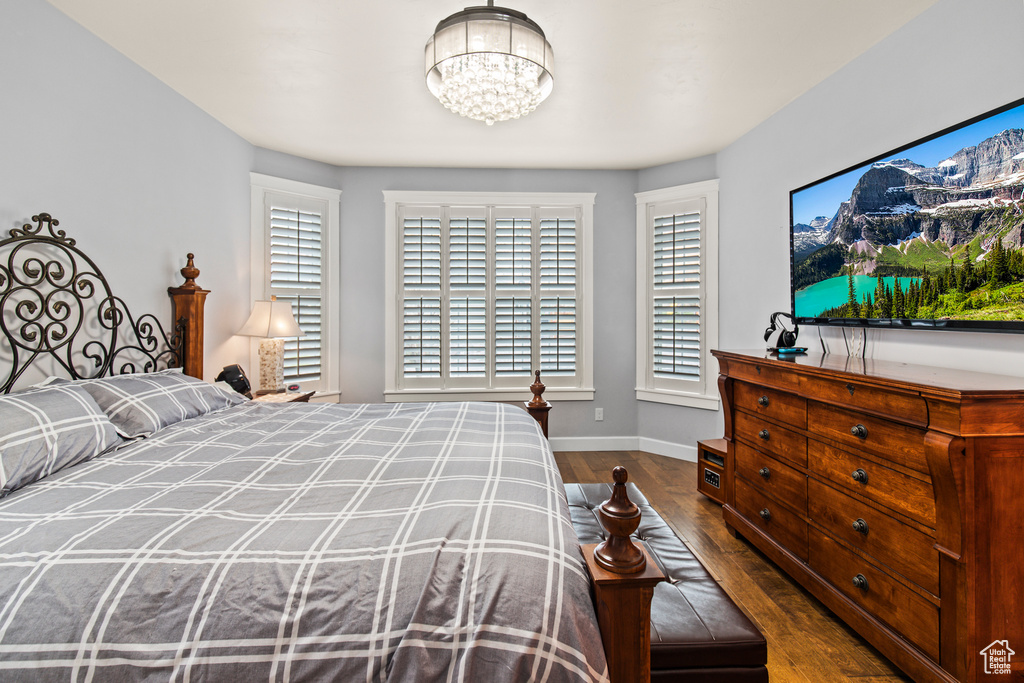 Bedroom with dark wood-type flooring and an inviting chandelier