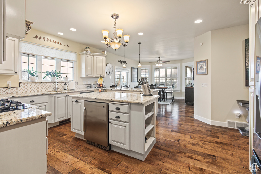 Kitchen with white cabinets, a center island, dark wood-type flooring, and a wealth of natural light