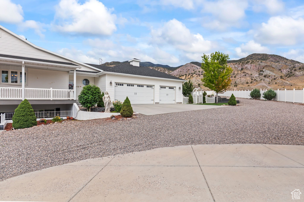 View of side of home featuring an attached garage, a mountain view, concrete driveway, and covered porch