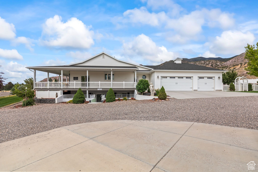 View of front facade featuring covered porch, concrete driveway, an attached garage, and a mountain view