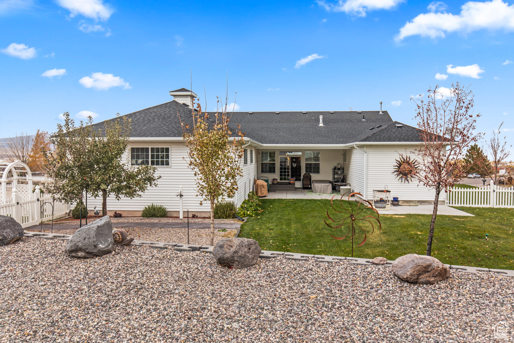 Rear view of house with a lawn and a patio