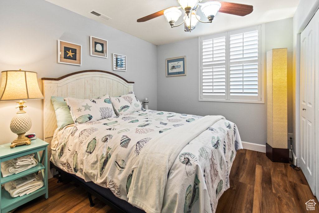 Bedroom with ceiling fan, dark wood-type flooring, and a closet