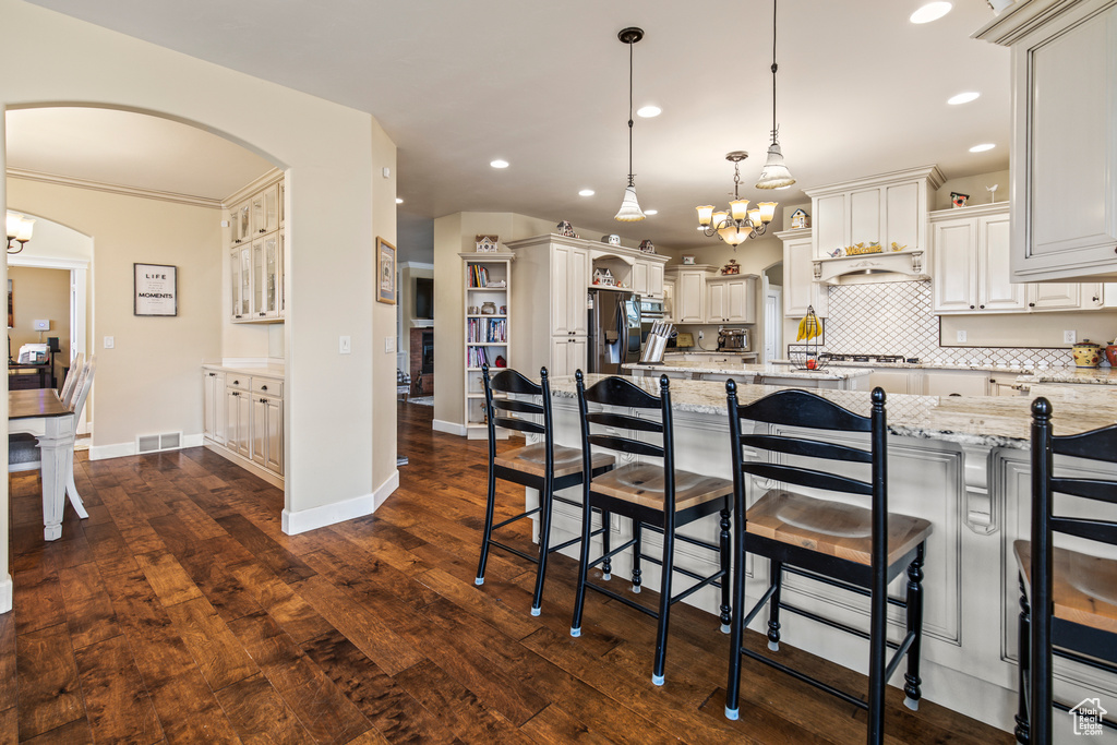 Kitchen with light stone countertops, pendant lighting, dark hardwood / wood-style flooring, and a kitchen breakfast bar