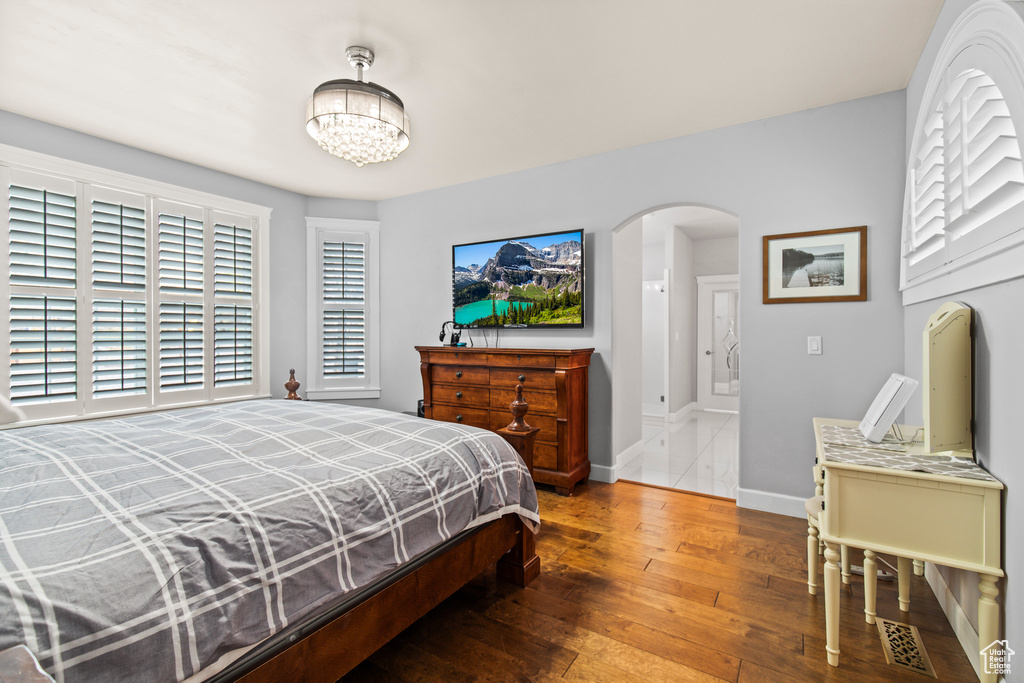 Bedroom featuring hardwood / wood-style floors, a chandelier, and multiple windows