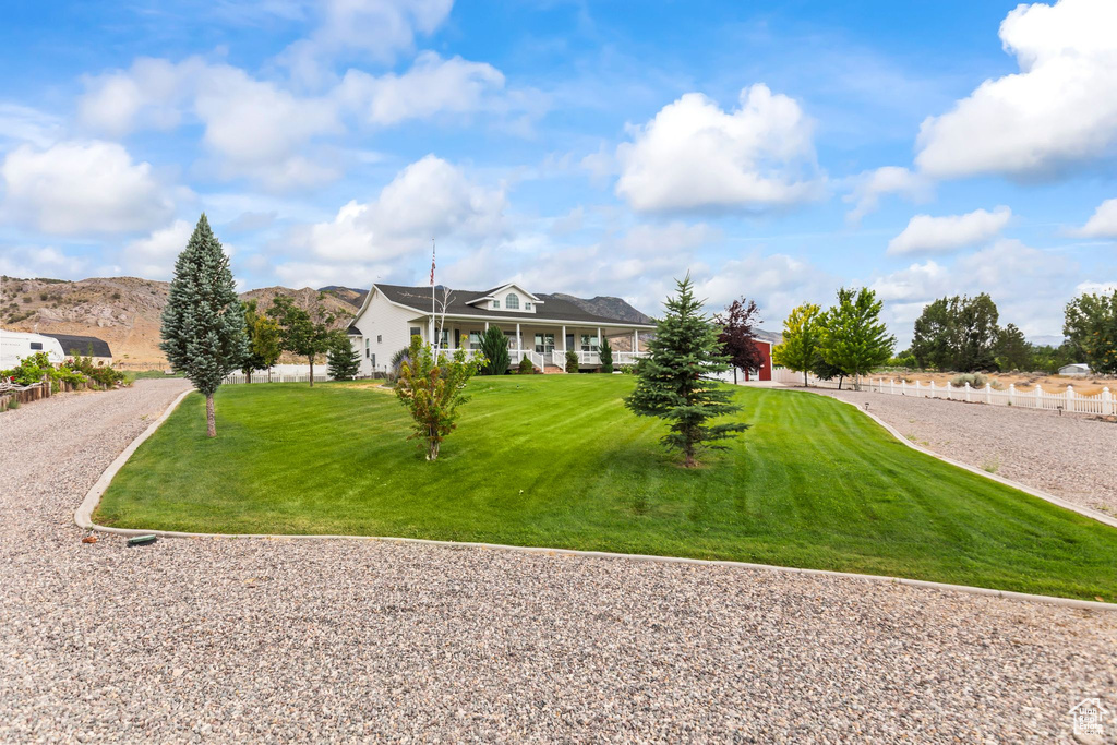 View of front of house with a front lawn, covered porch, and a mountain view