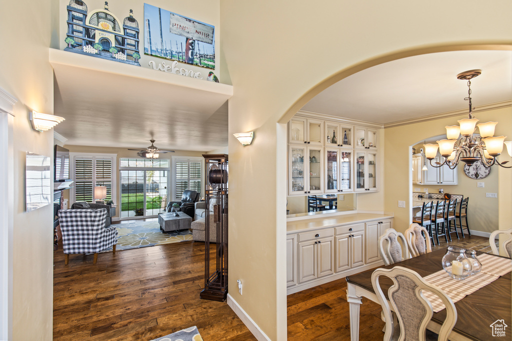 Dining area with dark hardwood / wood-style floors, ornamental molding, and ceiling fan with notable chandelier
