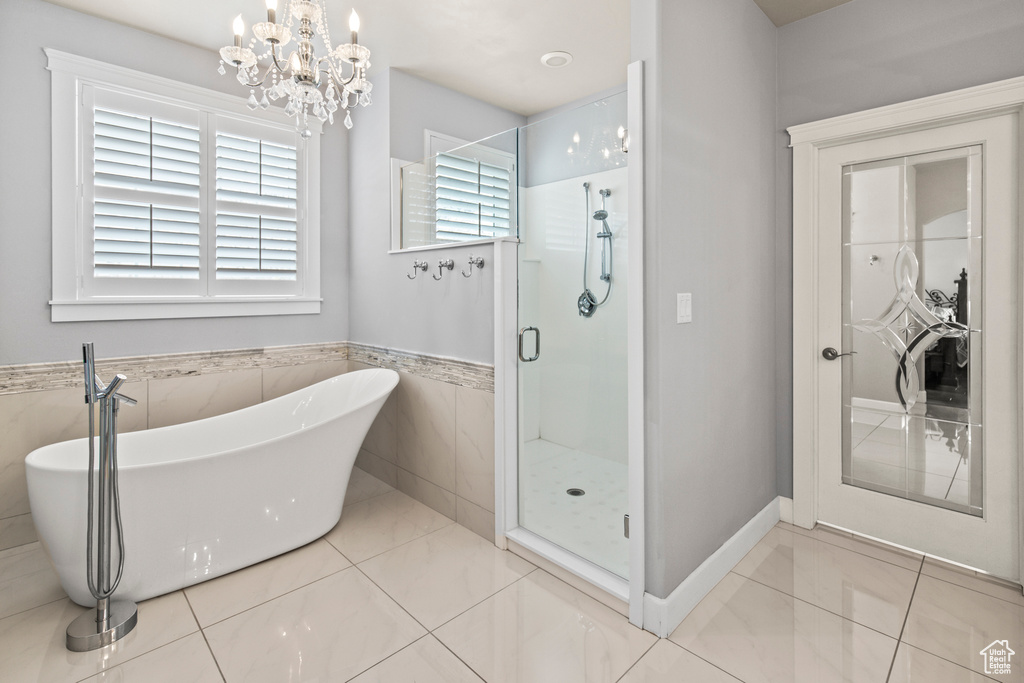 Bathroom with tile patterned floors, independent shower and bath, and an inviting chandelier