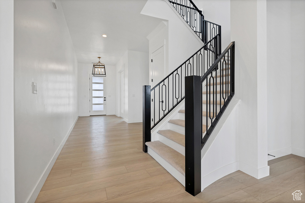 Stairs featuring wood finished floors, a chandelier, and recessed lighting