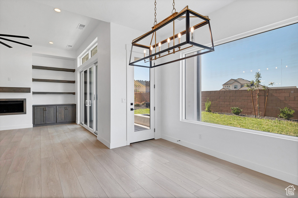 Unfurnished dining area with wood finished floors, recessed lighting, a fireplace, and a chandelier