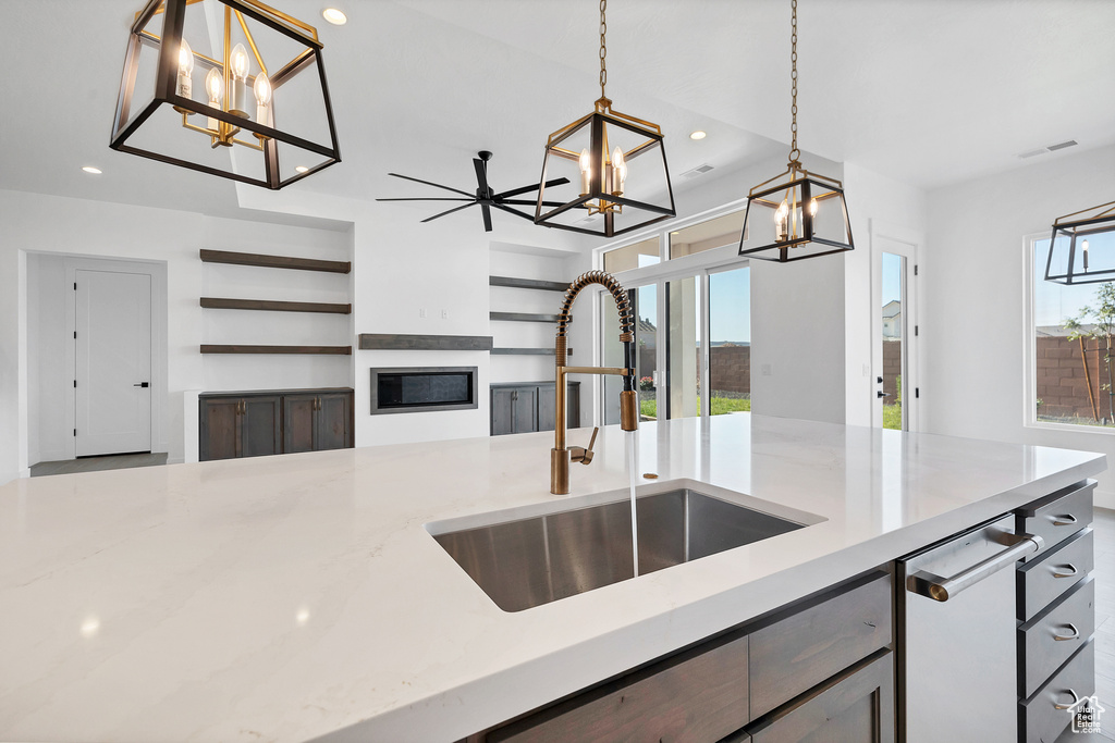 Kitchen featuring a chandelier, recessed lighting, decorative light fixtures, a glass covered fireplace, and light stone countertops