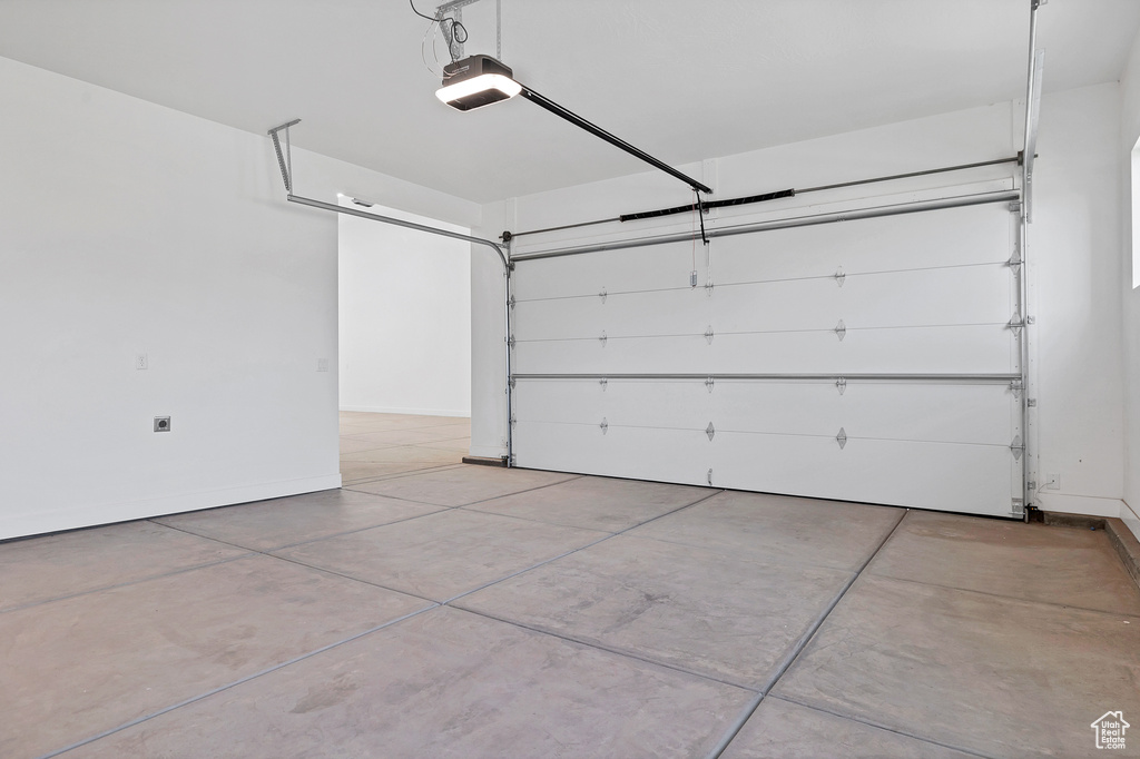Garage featuring a garage door opener and baseboards
