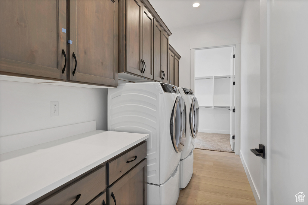 Washroom with washer and dryer, light wood-style flooring, cabinet space, and recessed lighting