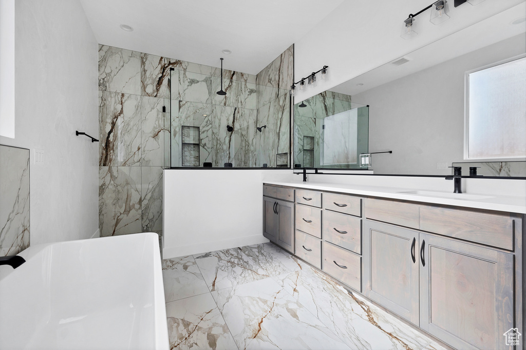 Full bathroom featuring marble tiled flooring, double vanity, a marble finish shower, and a freestanding tub