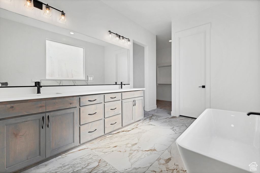 Full bathroom with marble tiled floors, double vanity, and a freestanding tub